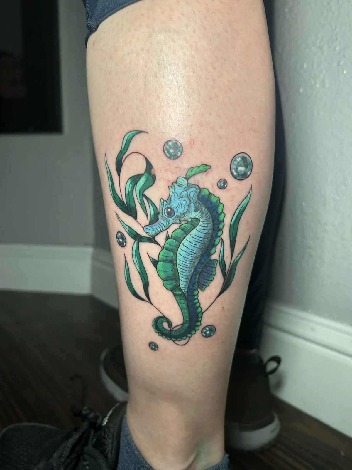 Fresh color seahorse tattoo with seaweed and bubbles on a calf