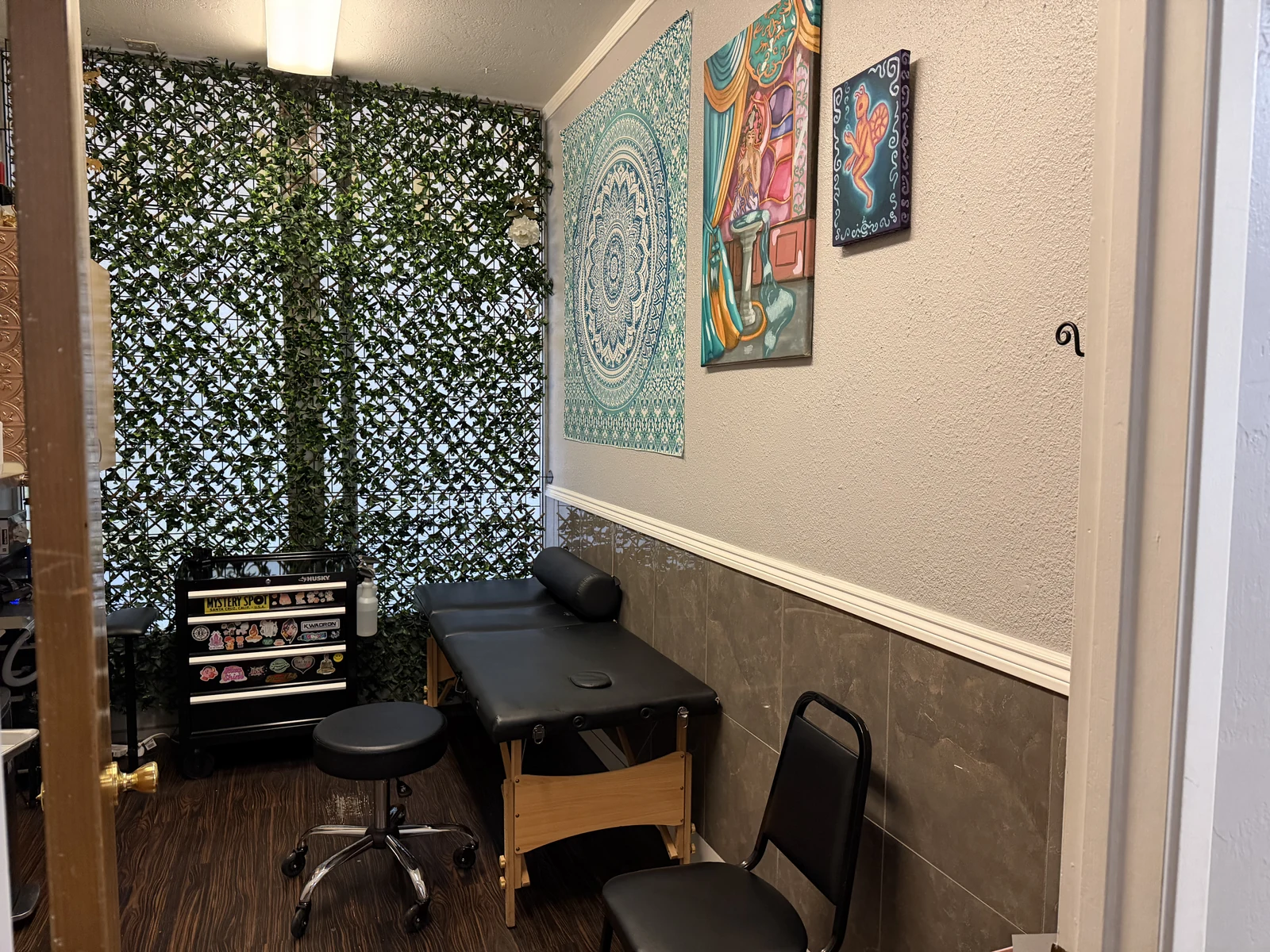 Juniper's studio room with a tattoo chair, artwork and a leafy divider